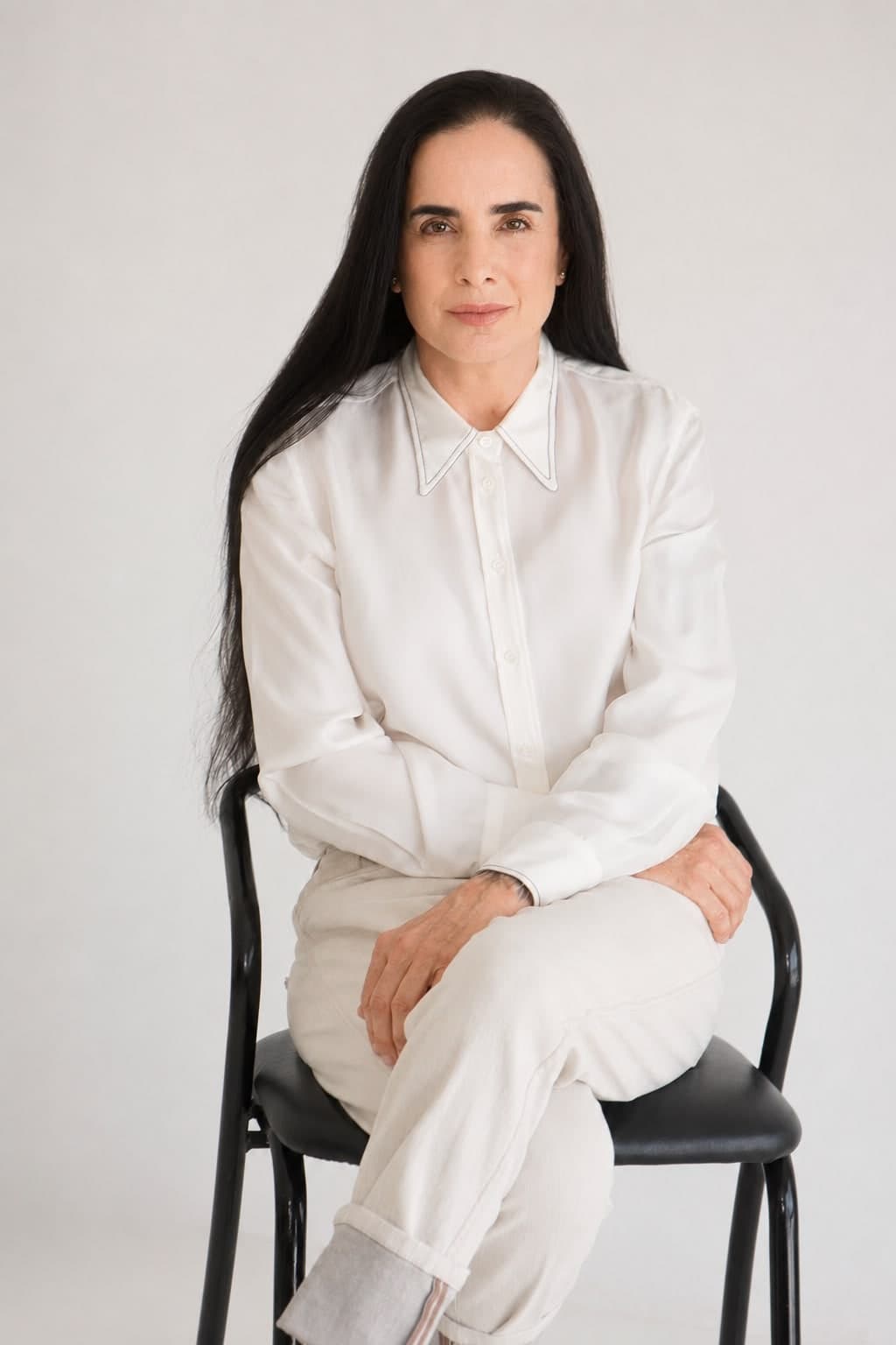 Isha Judd, retrato de estudio sentada en una silla, con camisa blanca